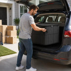 Black fabric storage bin with wide-open lid showing folded blanket being placed inside — wide opening easy to pack and access