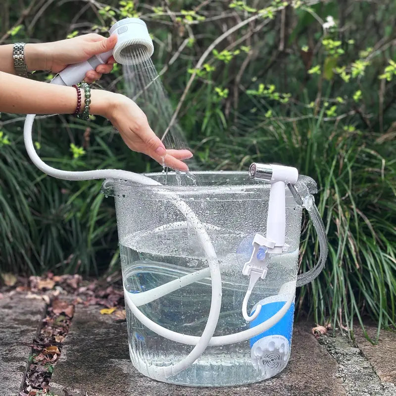 Portable electric shower pump drawing water from a bucket outdoors