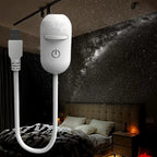 Hand holding compact white galaxy projector glowing warm yellow — portable compact design for bedroom, desk and travel